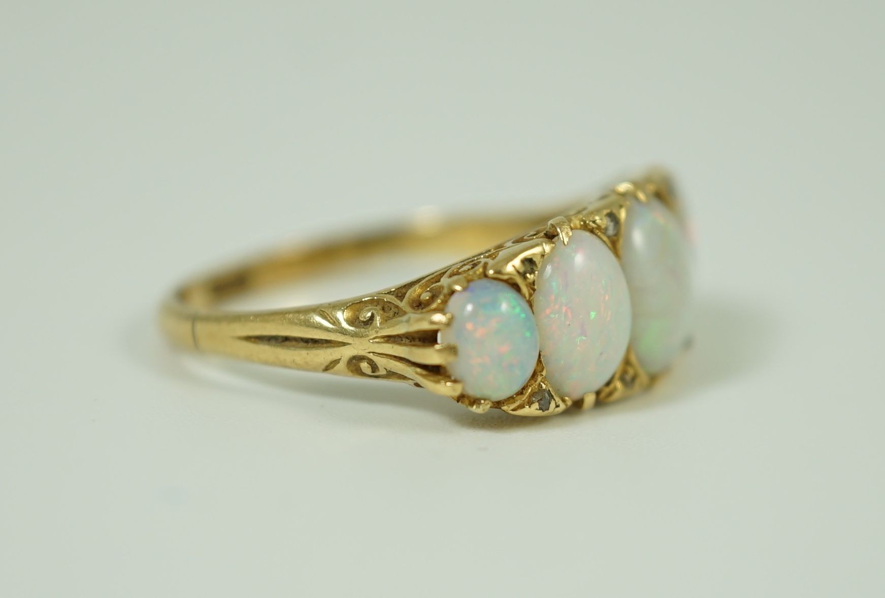 An 18ct gold and graduated five stone opal half hoop ring, with diamond chip spacers